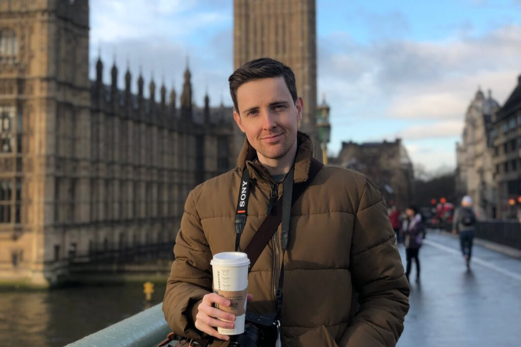 Young man holding coffee near Big Ben in London, UK. {{brizy_dc_image_alt imageSrc=