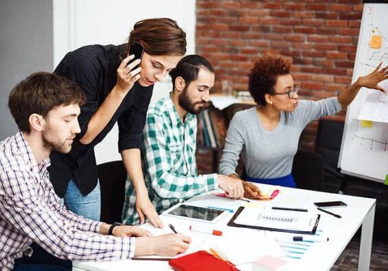 Team working together on a project with laptops and documents. {{brizy_dc_image_alt imageSrc=